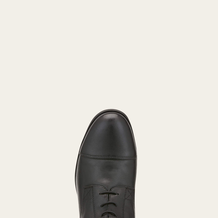 Black leather dress shoe on a light beige background