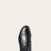 Black leather dress shoe on a light gray background