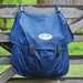 A blue waterproof blanket bag hanging on a weathered wooden fence outdoors, with a visible WeatherBeeta logo patch on the front flap.