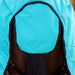 A close-up rear view of a horse wearing a bright turquoise turnout blanket with black trim and straps, showing off the tail flap and leg guards in black set against a wooden fence background.
