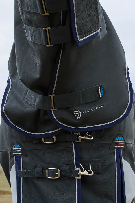 Close-up of the front of a  dark gray protective horse hood and blanket with navy blue trim, white piping, and silver buckle hardware. The brand name 'PROTECTION' with a shield logo is visible on the front flap.