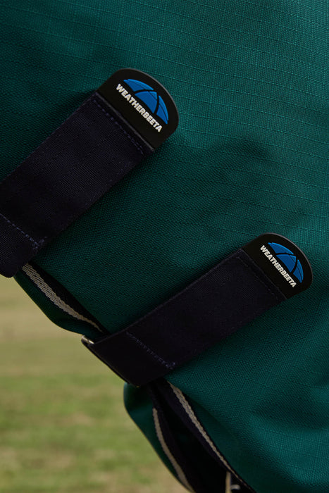Close-up of a dark forest green  waterproof neck rug with two black WeatherBeta strap closures and the WeatherBeta logo patch visible on each strap.
