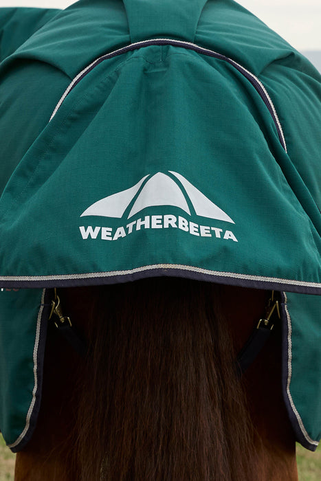 Close-up of a horse wearing a green Weatherbeeta horse blanket with a white logo on the tail flap and dark brown horse hair visible underneath.