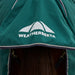 Close-up of a horse wearing a green Weatherbeeta horse blanket with a white logo on the tail flap and dark brown horse hair visible underneath.
