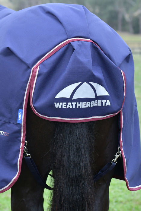 A navy blue and burgundy horse turnout blanket showing the tail flap and leg straps attached with silver metal claps featuring the WeatherBeeta logo in white on the front flap, shown on a horse outdoors.