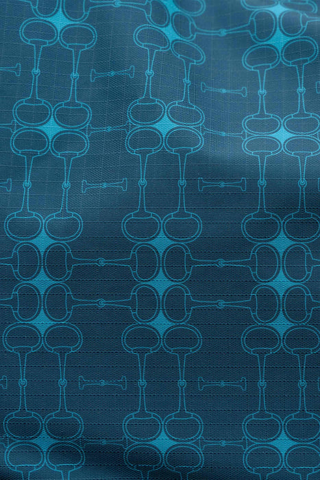 A close-up of a blue patterned fabric with a repeating geometric english bit design in lighter blue and cyan tones.