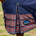 Close-up of a horse blanket on a horse, showing navy blue fabric with a red, white, and blue geometric patterned lower section and a visible WeatherBeta logo patch.