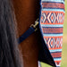 Close-up of a horse's brown coat and dark tail with a navy blue patterned turnout blanket draped over the rump, featuring geometric orange, white, and blue woven-style motifs.