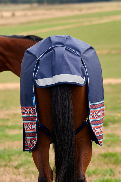 A navy blue horse turnout blanket with red, white, and blue geometric patterned trim, shown on the back of a brown horse in an outdoor grassy field.