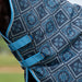 Close-up of a horse turnout blanket with a navy blue and teal geometric pattern, featuring blue straps and trim.