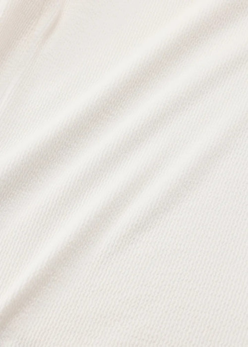 A close-up of a soft, off-white or cream-colored fabric with a fine ribbed texture and gentle diagonal folds.