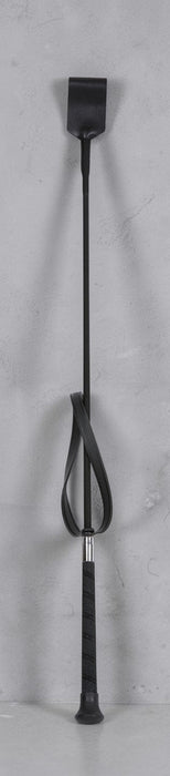 A black riding crop with a textured grip handle and a black leather loop, shown against a light gray textured background.