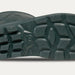 A close-up of a dark green boot sole showing its tread pattern, photographed against a light gray background.