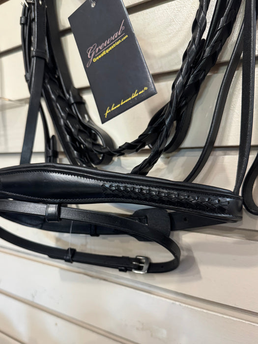 A black leather horse bridle with an attached bit and reins hanging on a retail display wall. A black hangtag with gold script branding is attached near the top.