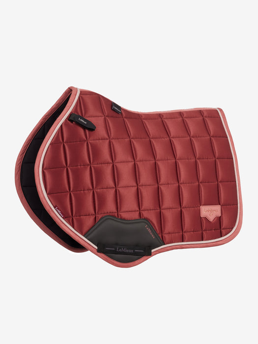 A quilted equestrian saddle pad in a dusty rose orange color, featuring a diamond-quilted pattern, a black protective under-rib pad, and a light coral stitched border, shown against a plain light gray background.