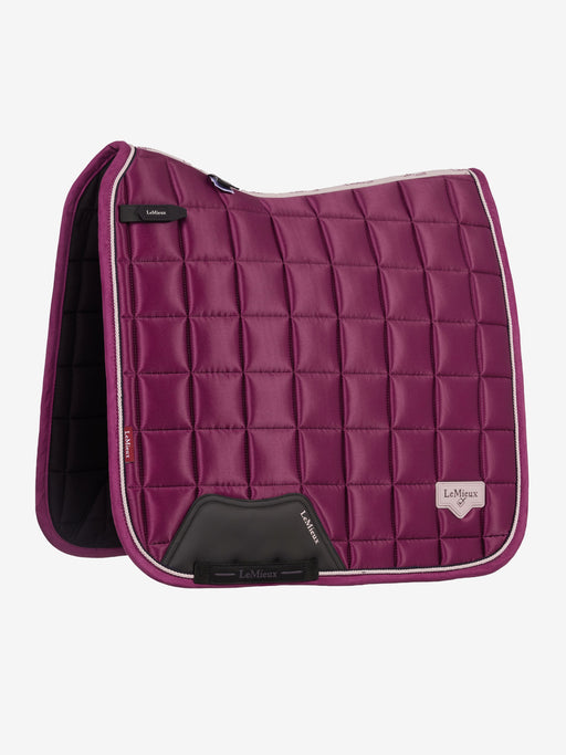 A LeMieux quilted horse saddle pad in a deep magenta-purple color, featuring a diamond-quilted pattern, white piping, and black leather accents, shown against a light gray background.