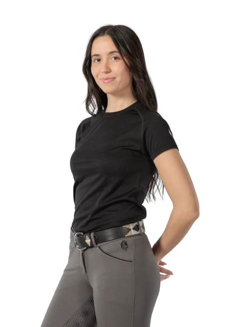 A woman modeling a black short-sleeve athletic t-shirt and gray riding breeches with a patterned belt, photographed against a solid white background.