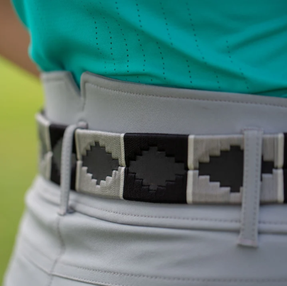 A close-up of a person wearing a light gray belt with black geometric pixelated patterns, paired with a turquoise top and light gray pants.
