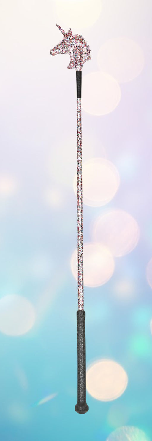 A unicorn-themed riding crop with a sparkly unicorn head at the top, a long sparkly shaft, and a dark textured handle, shown against a soft pastel bokeh background.