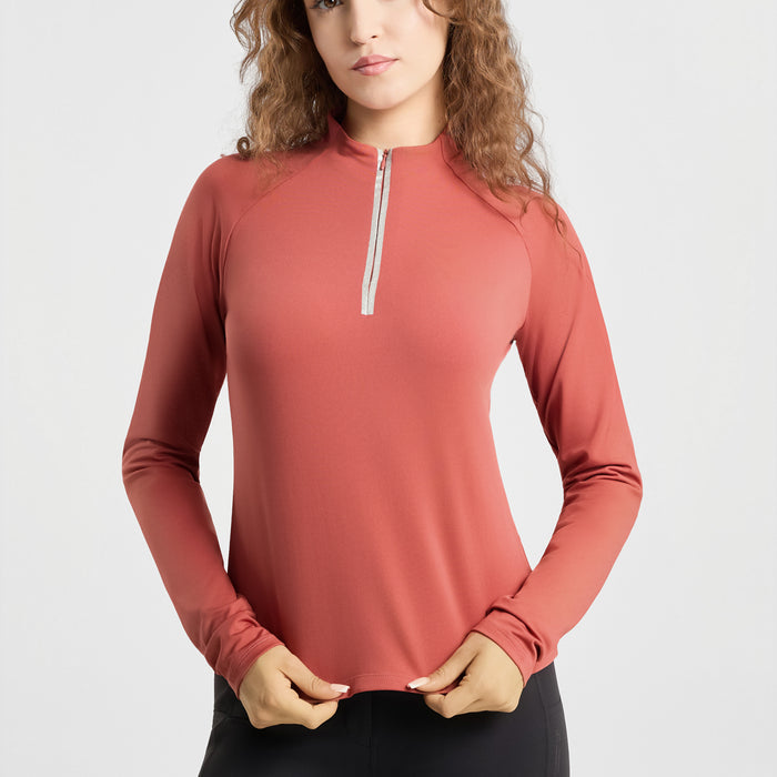 A woman wearing a long-sleeve athletic quarter-zip top in a muted terracotta or dusty rose color, paired with black bottoms, against a clean light gray studio background.