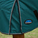 Close-up of a green horse blanket with Weatherbeeta logo on a grassy background