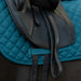 A close up of a blue cotton quilted saddle pad under a dressage saddle on a dark brown horse 