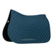A close up of a blue cotton quilted dressage saddle pad against a white back ground