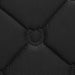 Close-up of a black quilted fabric with diamond stitching and a circular tufted horseshoe detail in the center.